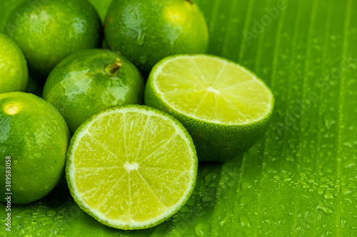 Close up pile of half and whole fresh lime juicy on green banana leaves with clearly water drop on surface