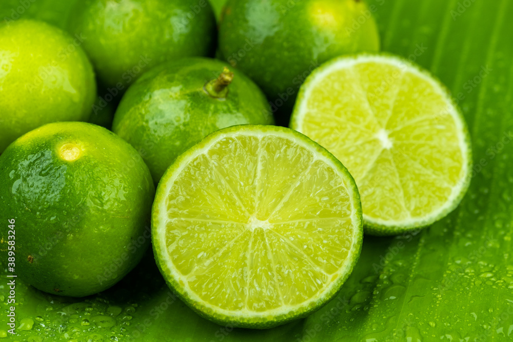 Close up pile of half and whole fresh lime juicy on green banana leaves with clearly water drop on surface Close up pile of half and whole fresh lime juicy on green banana leaves with clearly water drop on surface