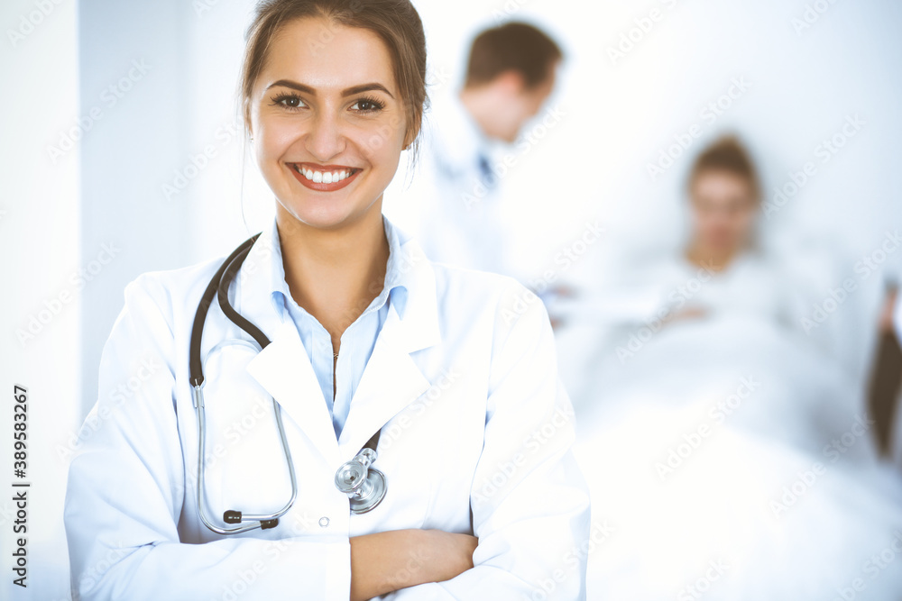 Female doctor smiling on the background with patient in the bed and two doctors Female doctor smiling on the background with patient in the bed and two doctors