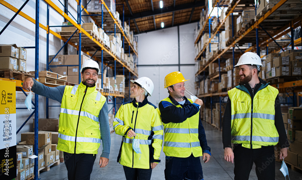 Group of workers taking face masks off indoors in warehouse, coronavirus concept. Group of workers taking face masks off indoors in warehouse, coronavirus concept.