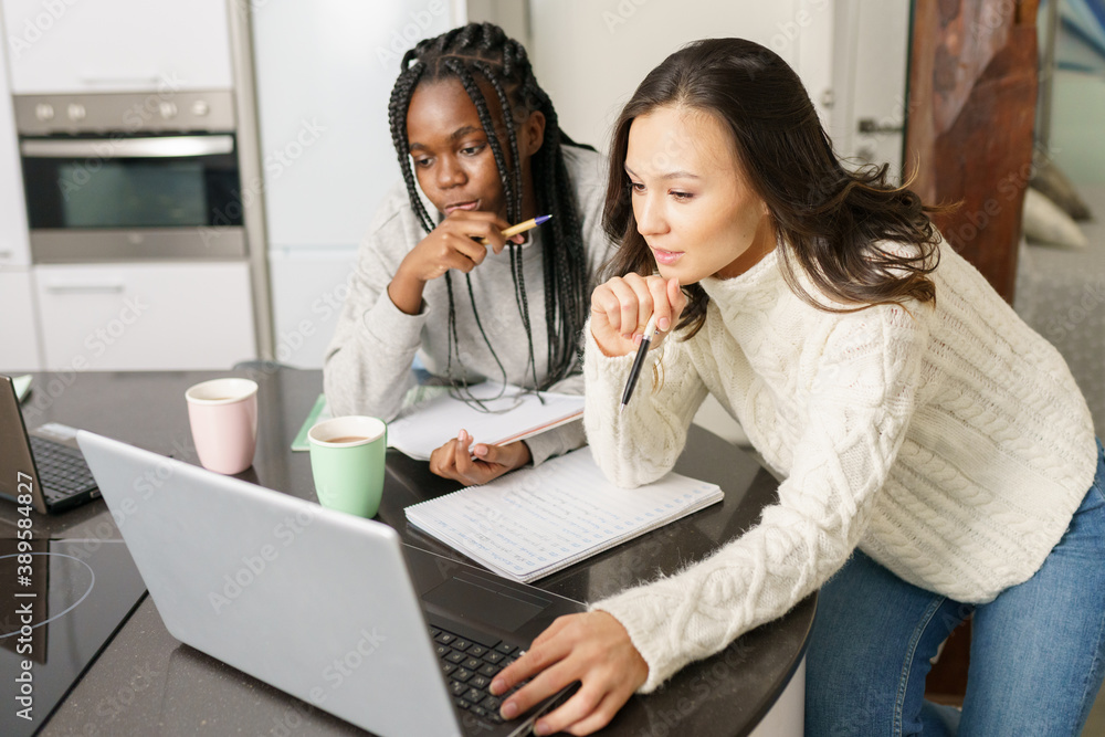 Two college girls studying together at home with laptops while drinking coffee Two college girls studying together at home with laptops while drinking coffee