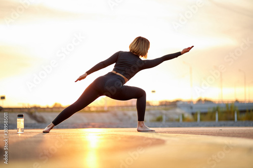 sporty fit caucasian woman doing ashtanga vinyasa yoga asana virabhadrasana 1 warrior pose outdoors, young female in sportswear