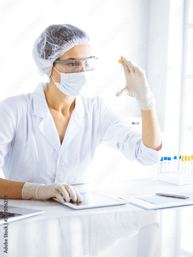 Professional female scientist in protective eyeglasses researching tube with reagents in laboratory. Concepts of medicine and science researching Professional female scientist in protective eyeglasses researching tube with reagents in laboratory. Concepts of medicine and science researching