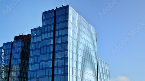 Blue curtain wall made of toned glass and steel constructions under blue sky. A fragment of a building.