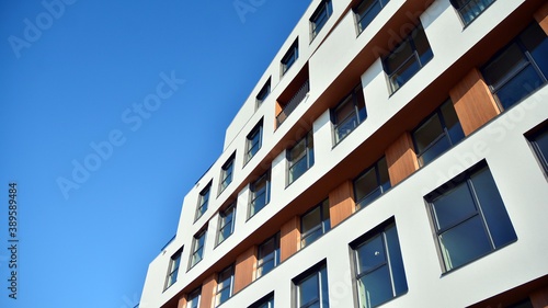 Modern and new apartment building. Multistoried modern, new and stylish living block of flats. Facades on a bright sunny day with sunbeams in the blue sky.