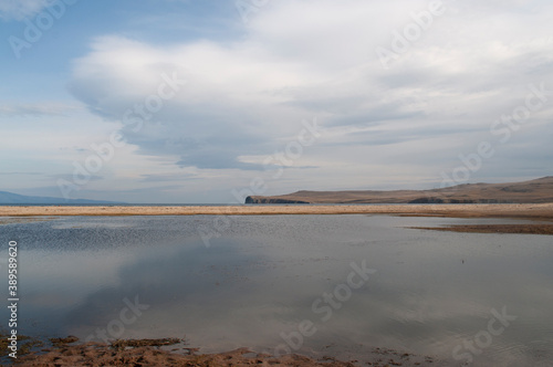 Baikal lake fresh water flora shore reserve Russia Irkutsk park island Sky clouds clear Olkhon rocks trees embankments sand bay lagoon stones mountains hills horizon line panorama autumn water waves 