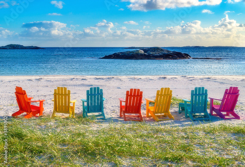 Colorful chairs on a row in sand