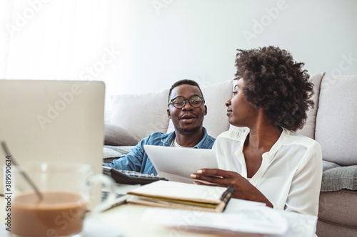Young married couple doing their paperwork together, paying bills online. Focus on the guy. Loving young couple using laptop and analyzing their finances. Writing notes.