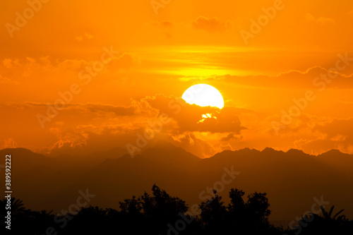 Landscape, sun behind the clouds at sunset