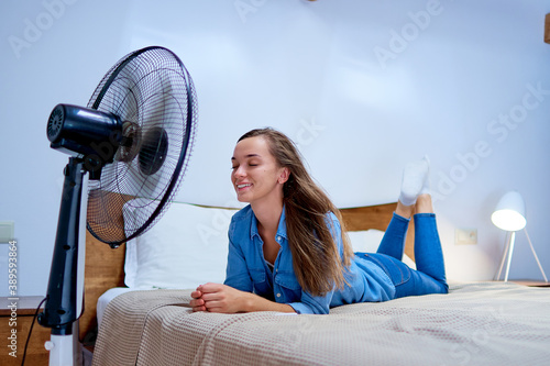 Fotografija Smiling young cute woman lying in bed in the bedroom in sunny hot summer day and