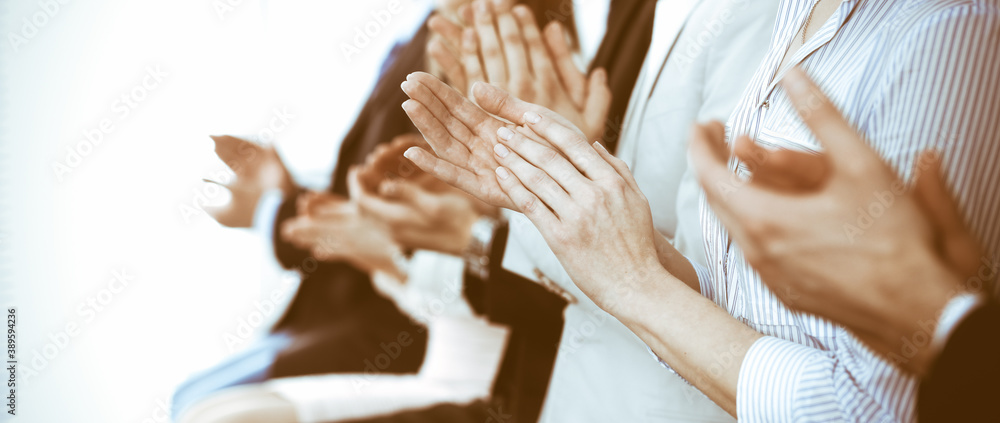 Obraz premium Business people clapping and applause at meeting or conference, close-up of hands. Group of unknown businessmen and women in modern white office. Success teamwork or corporate coaching concept