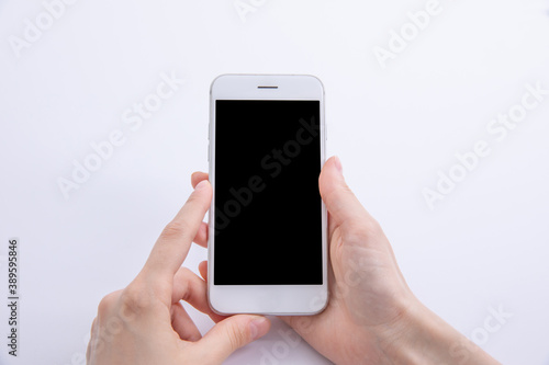 female hands holding new modern black smartphone isolated on white background, close view . High quality photo