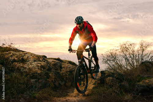 Obraz na plátně Cyclist in Red Riding Bike on the Autumn Rocky Trail at Sunset