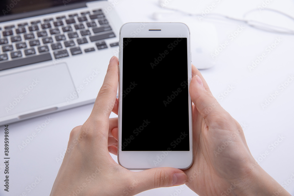 top view of female hands using smartphone over desktop with laptop , work concept . High quality photo