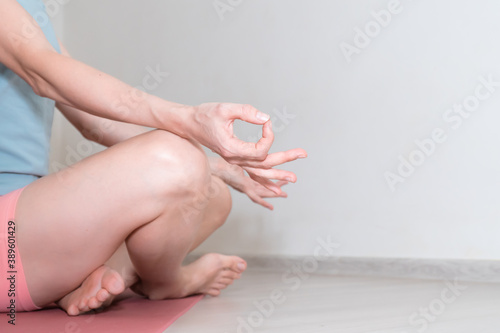 hands and legs of woman doing yoga. Lady sit on mat meditating and practicing yoga at home