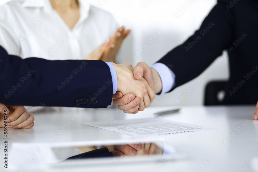 Business people shaking hands at meeting or negotiation, close-up. Group of unknown businessmen, and a woman on the background in a modern office. Teamwork, partnership and handshake concept Business people shaking hands at meeting or negotiation, close-up. Group of unknown businessmen, and a woman on the background in a modern office. Teamwork, partnership and handshake concept