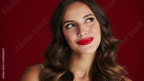 Wallpaper Mural A close-up view of a pretty woman is dreaming about something standing isolated over a red background in the studio Torontodigital.ca