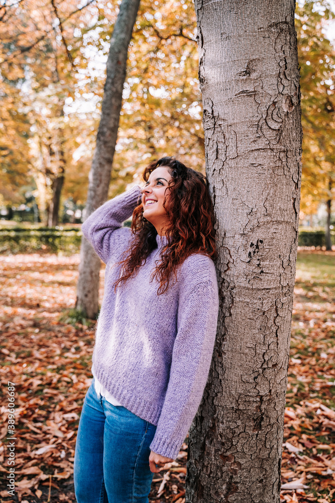 A beautiful woman having fun in the park in a sunny autumnal day. She wearing a sweater and jeans. She is looking up to the sky. Lifestyle in autumnal outdoors A beautiful woman having fun in the park in a sunny autumnal day. She wearing a sweater and jeans. She is looking up to the sky. Lifestyle in autumnal outdoors