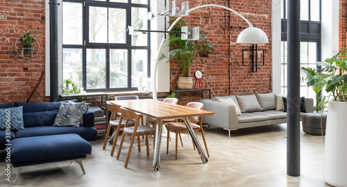 Interior of living room in industrial style in loft apartment. Brick wall  big wall  wooden table and navy sofa in stylish room at home. Banner.