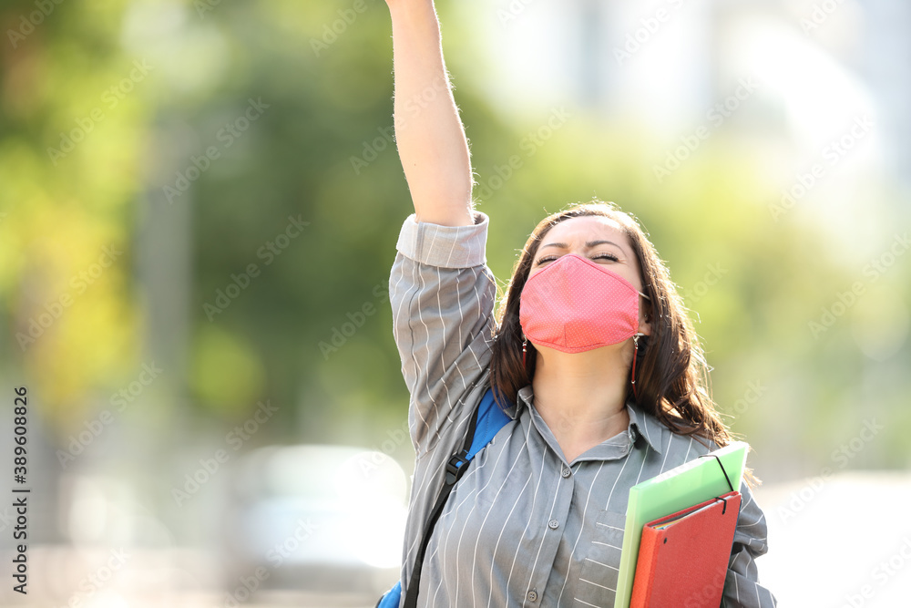 Naklejka premium Excited student wearing mask raising arm in the street