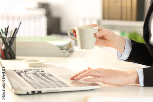 Executive hands holding coffee using laptop at office