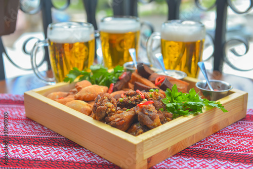 A large plate with a wide selection of snacks for beer. Three beer glasses in the background.