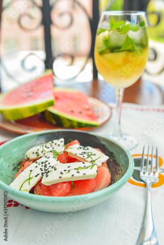 Greek watermelon salad with feta cheese and basil. Delicious summer meal in a restaurant outside, eating out concept.