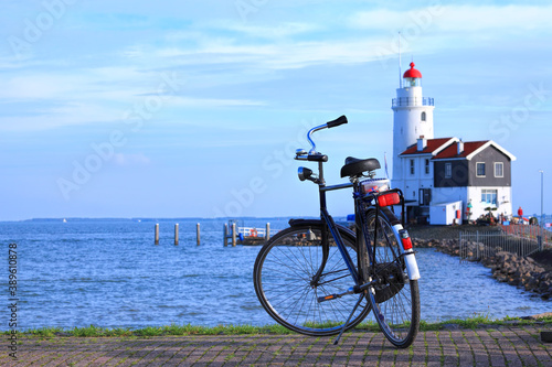 Blue sea harbor with bicycle parked on cobble stone pier against lighthouse on the seacoast. Magnificent blue sky over calm expanse on a sunny day. Netherlands. Panoramic view  photo