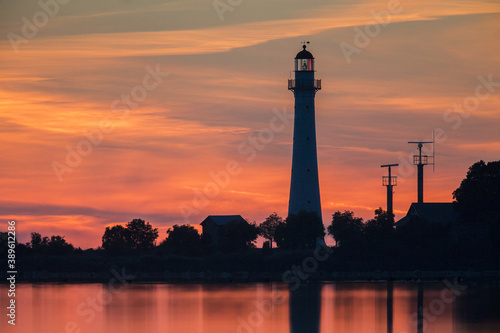 Sunset colored sky and water with the lighthouse and its mirror image photo