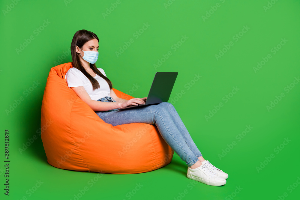 Profile photo of attractive lady hold computer wear medical mask t-shirt jeans sneakers isolated green background Profile photo of attractive lady hold computer wear medical mask t-shirt jeans sneakers isolated green background