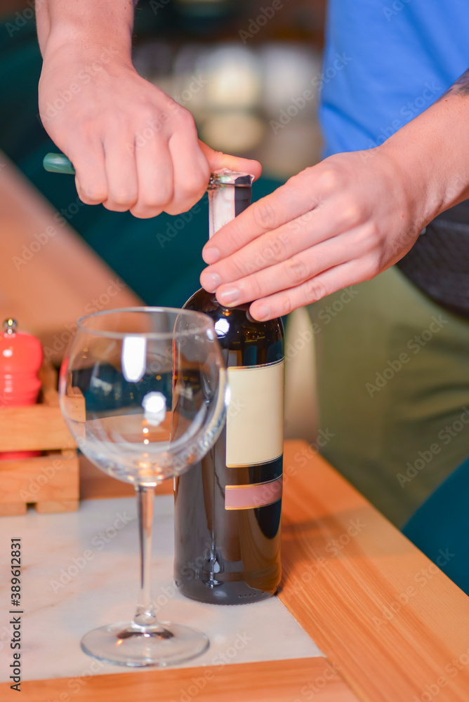 Wine glass and bottle of red wine on a wooden table over blurred background. Restaurant service, eating out concept. Wine glass and bottle of red wine on a wooden table over blurred background. Restaurant service, eating out concept.