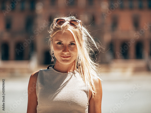 Blond Girl standing in Sevilla holding a Fan in front of her face Showing her Blond hair and Green brown Eyes