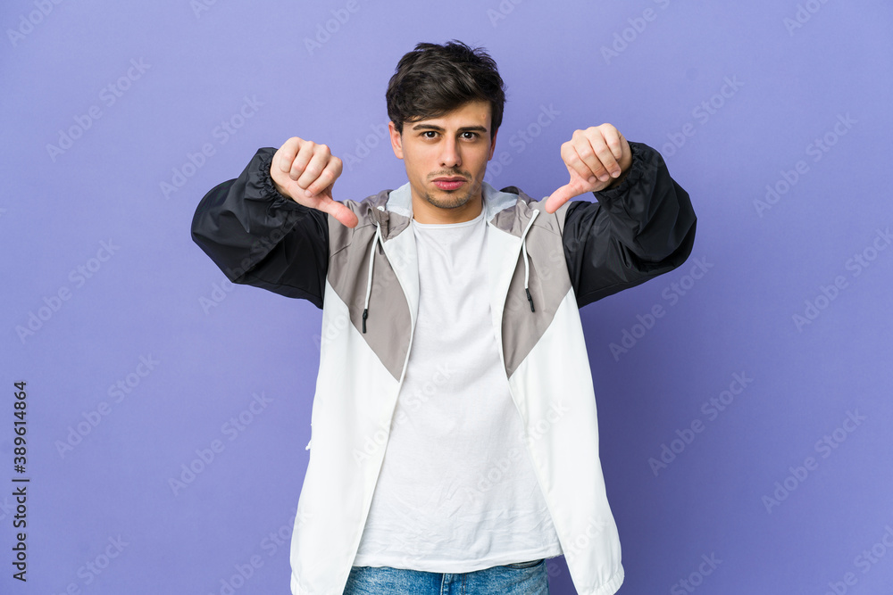 Young cool man showing a dislike gesture, thumbs down. Disagreement concept. Young cool man showing a dislike gesture, thumbs down. Disagreement concept.