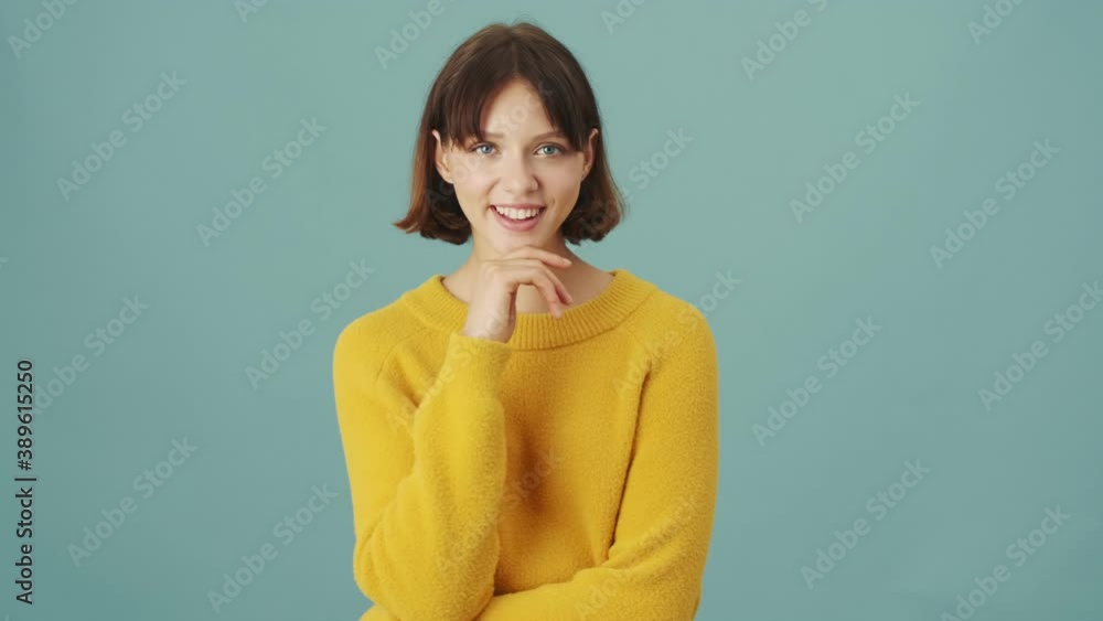 A dreaming woman is standing isolated over a blue background in the studio A dreaming woman is standing isolated over a blue background in the studio
