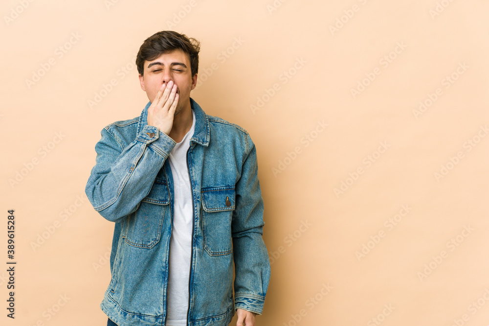 Fototapeta premium Young cool man yawning showing a tired gesture covering mouth with hand.