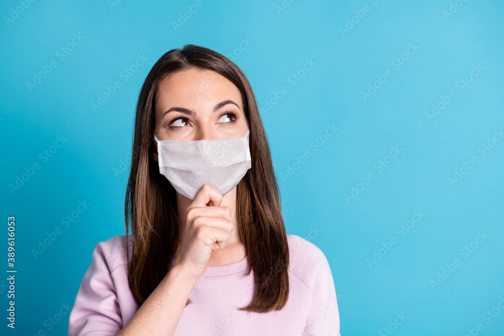 Photo of charming young lady finger chin look up empty space wear white face mask isolated blue color background Photo of charming young lady finger chin look up empty space wear white face mask isolated blue color background
