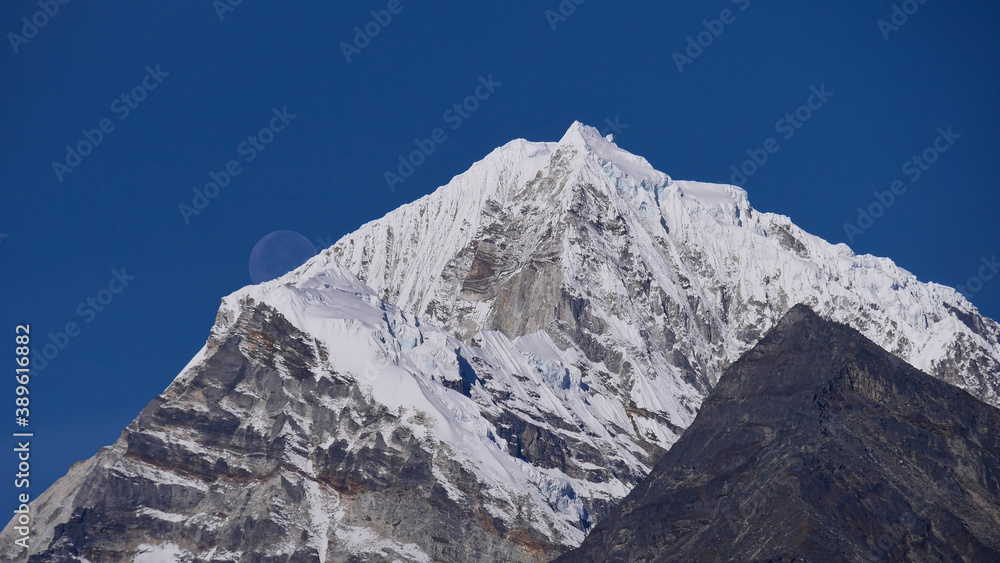 Stunning view of full moon rising above impressive snow-capped mountain Tengi Ragi Tau (peak 6,943 m) near Thame, Khumbu, Himalayas, Nepal.