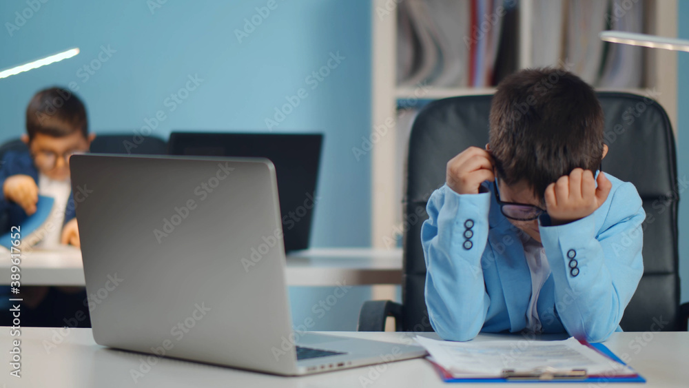Tired and stressed little businessman working on laptop at office. Tired and stressed little businessman working on laptop at office.