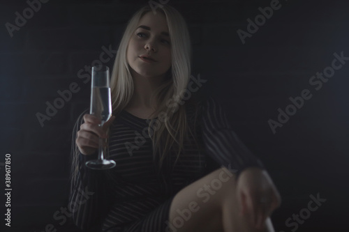 sexy blonde girl drinks champagne from a glass, evening glamorous style portrait