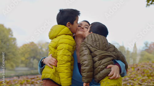 Adorable little boys kissing beautiful young mother outdoors © TommyStockProject
