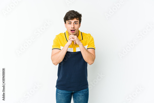 Young cool man praying for luck, amazed and opening mouth looking to front.