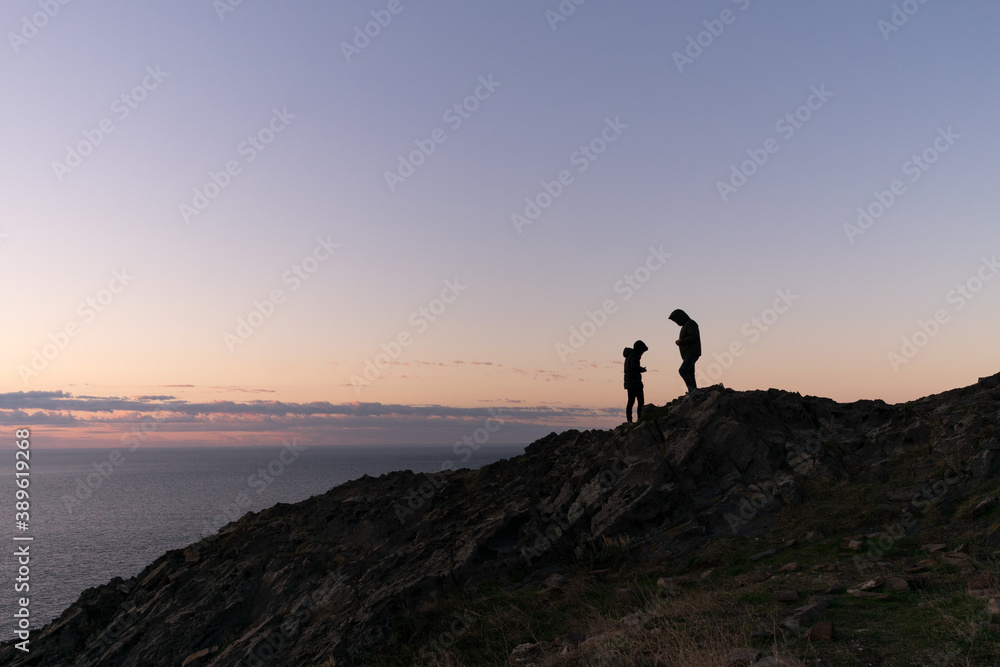 Silhouette of couple on mountain during sunrise.
