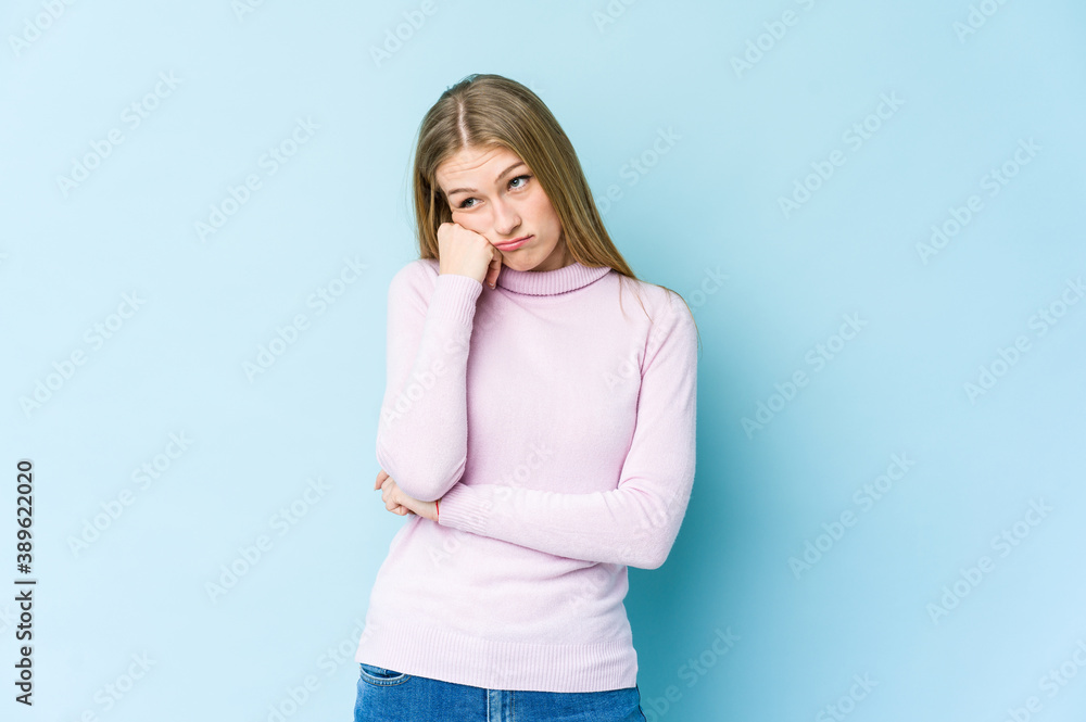 Young blonde woman isolated on blue background who feels sad and pensive, looking at copy space. Young blonde woman isolated on blue background who feels sad and pensive, looking at copy space.