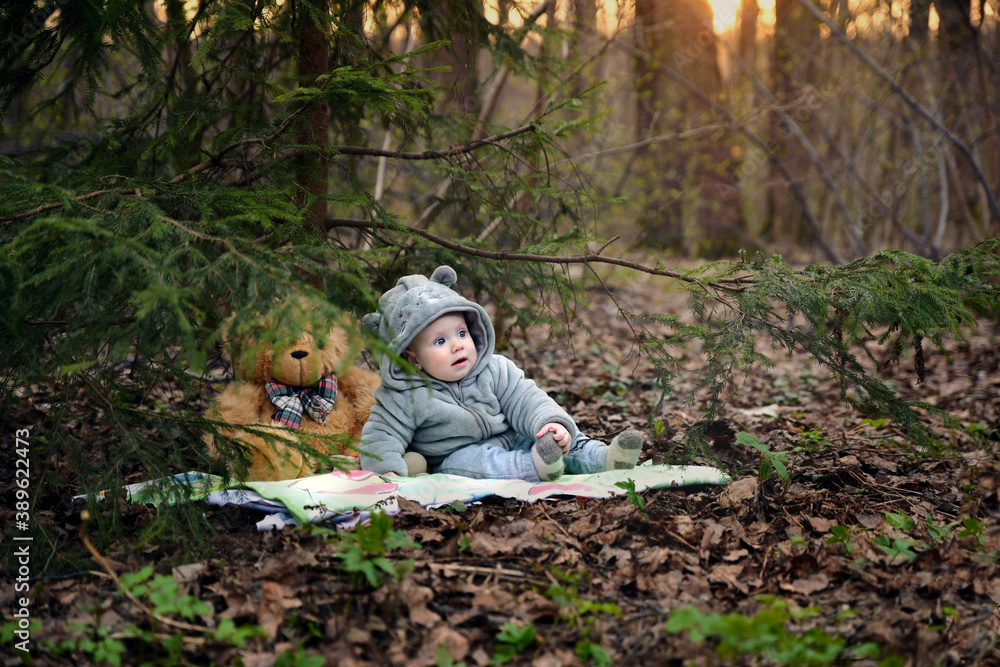 Naklejka premium Small child with a toy is resting in the park at sunset.