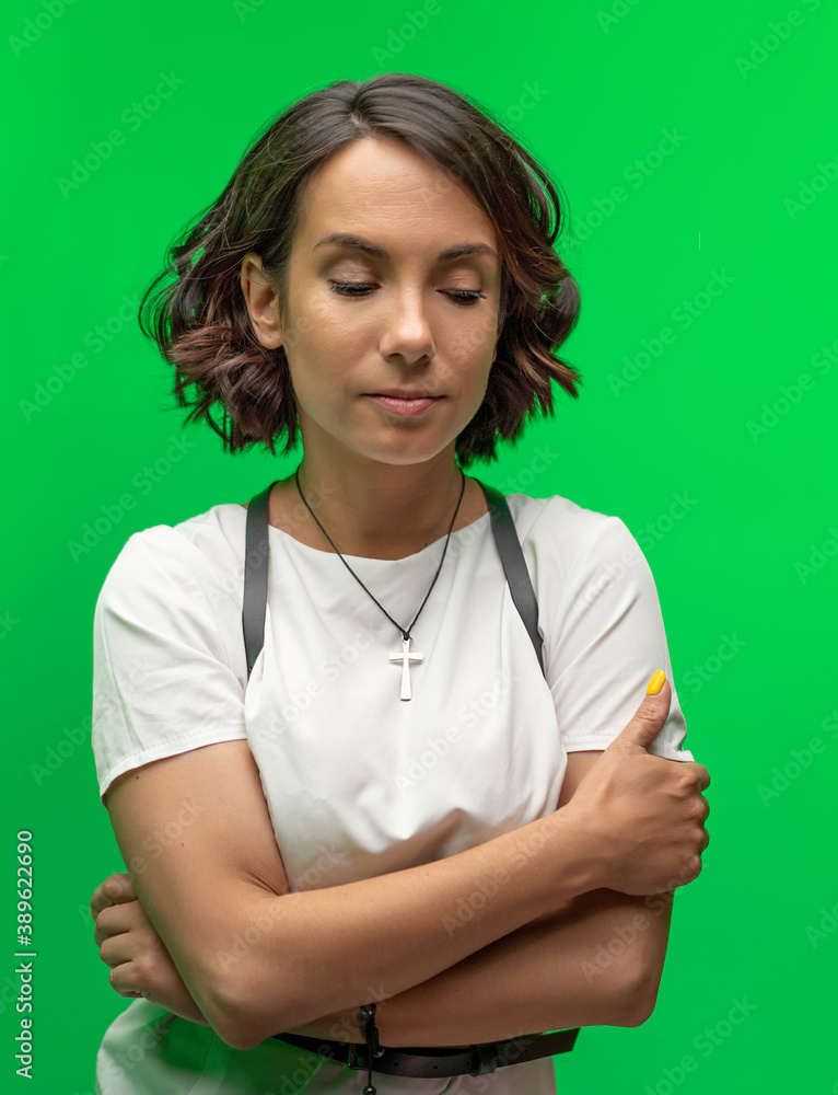 Young brunette woman looks down sits crossed arms. Cheerful female model with short dark hair isolated on chromakey or green background. High quality photo Young brunette woman looks down sits crossed arms. Cheerful female model with short dark hair isolated on chromakey or green background. High quality photo