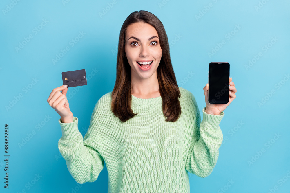 Photo portrait of girl demonstrating plastic bank debit card screen smartphone with copyspace isolated on vibrant blue color background Photo portrait of girl demonstrating plastic bank debit card screen smartphone with copyspace isolated on vibrant blue color background