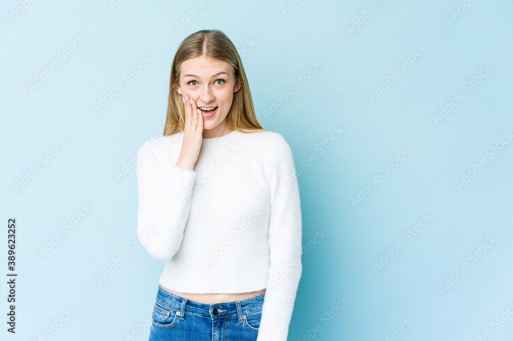 Young blonde woman isolated on blue background shouts loud, keeps eyes opened and hands tense. Young blonde woman isolated on blue background shouts loud, keeps eyes opened and hands tense.