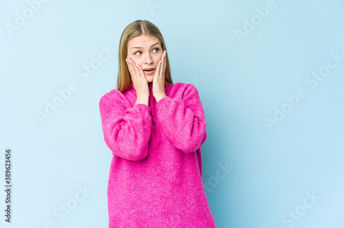 Young blonde woman isolated on blue background scared and afraid.