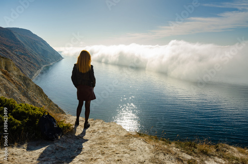 A girl stands on a hill and observes an unusual phenomenon of nature over the sea