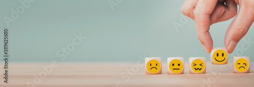 Hand chooses with happy smile face emoticon icons on Wooden Cube , good feedback rating for customer review survey photo
